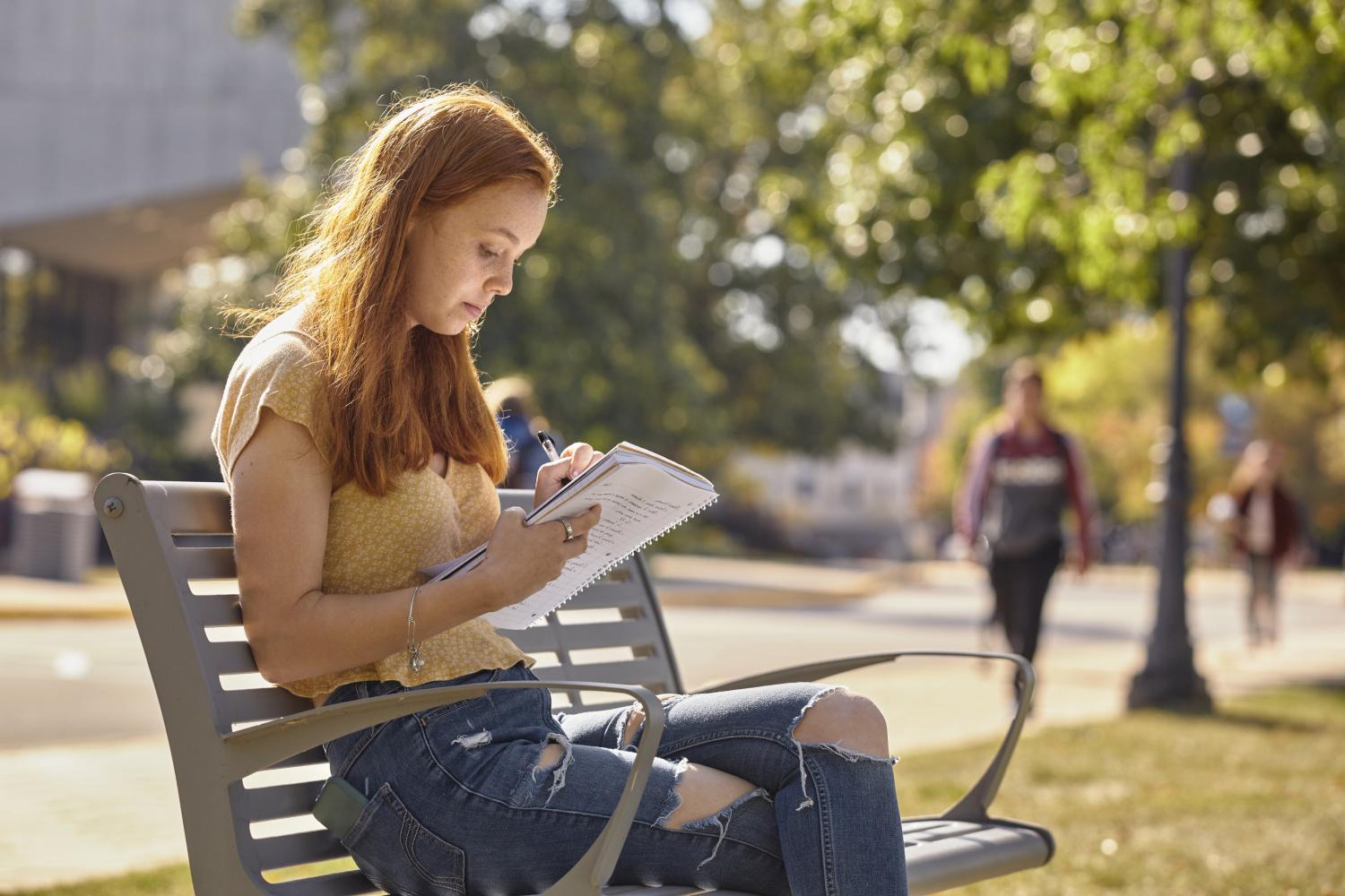 A <a href='http://3l8u.technestng.com'>博彩网址大全</a> student reads on a bench along Campus Drive.